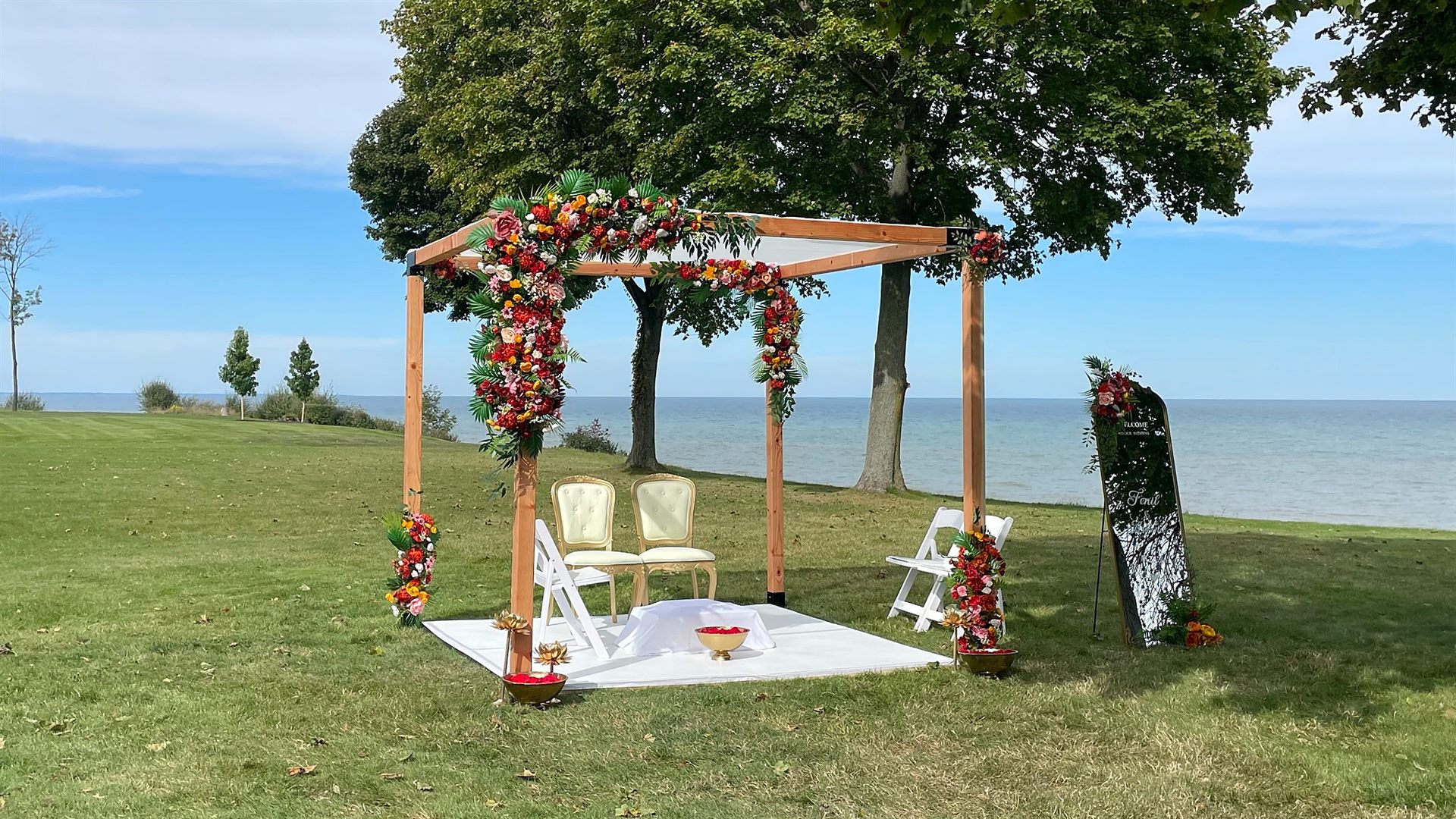 Wooden wedding arbor covered in colorful florals beside the lake