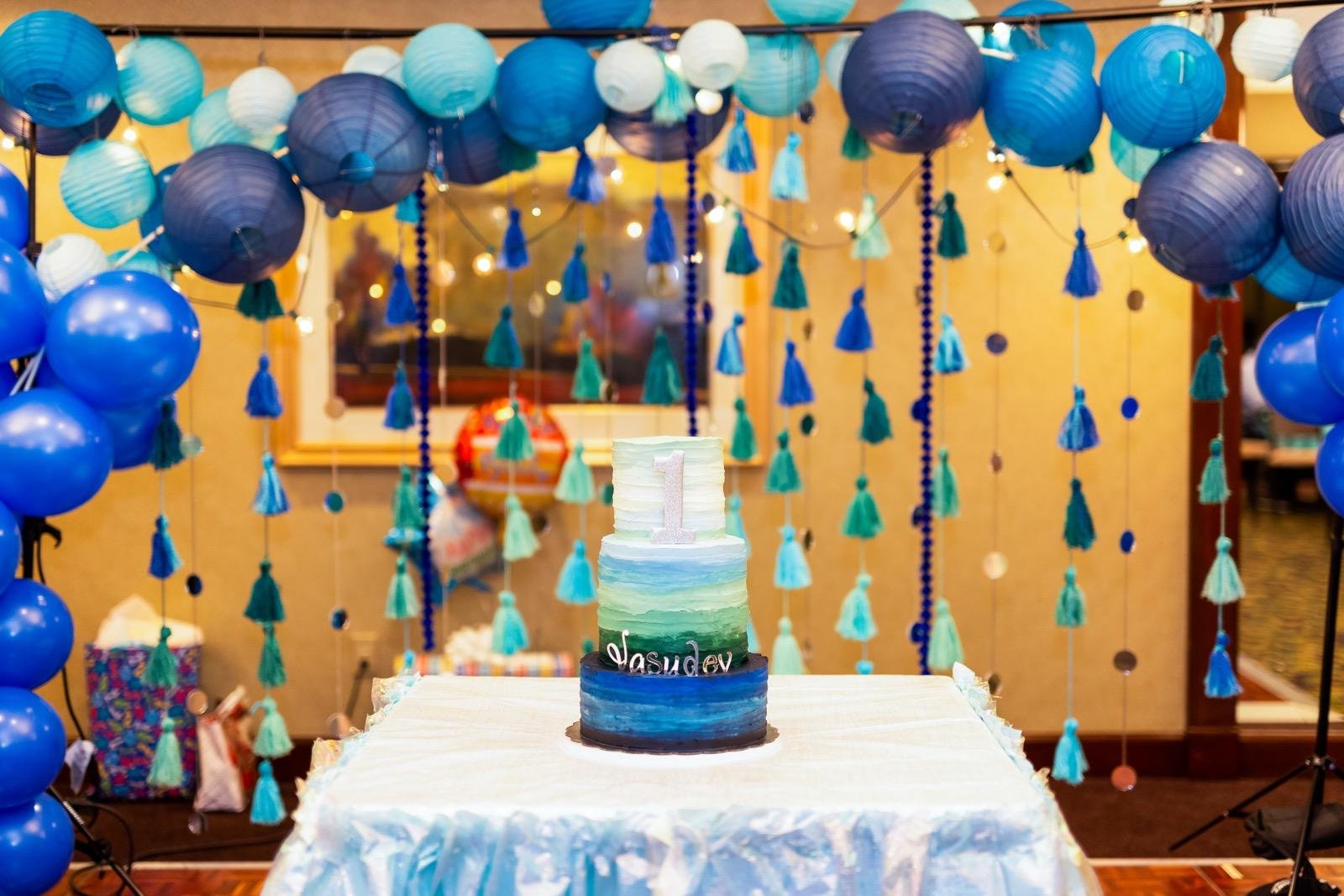 Ocean blue first birthday with paper lanterns, tassels, and ombre cake