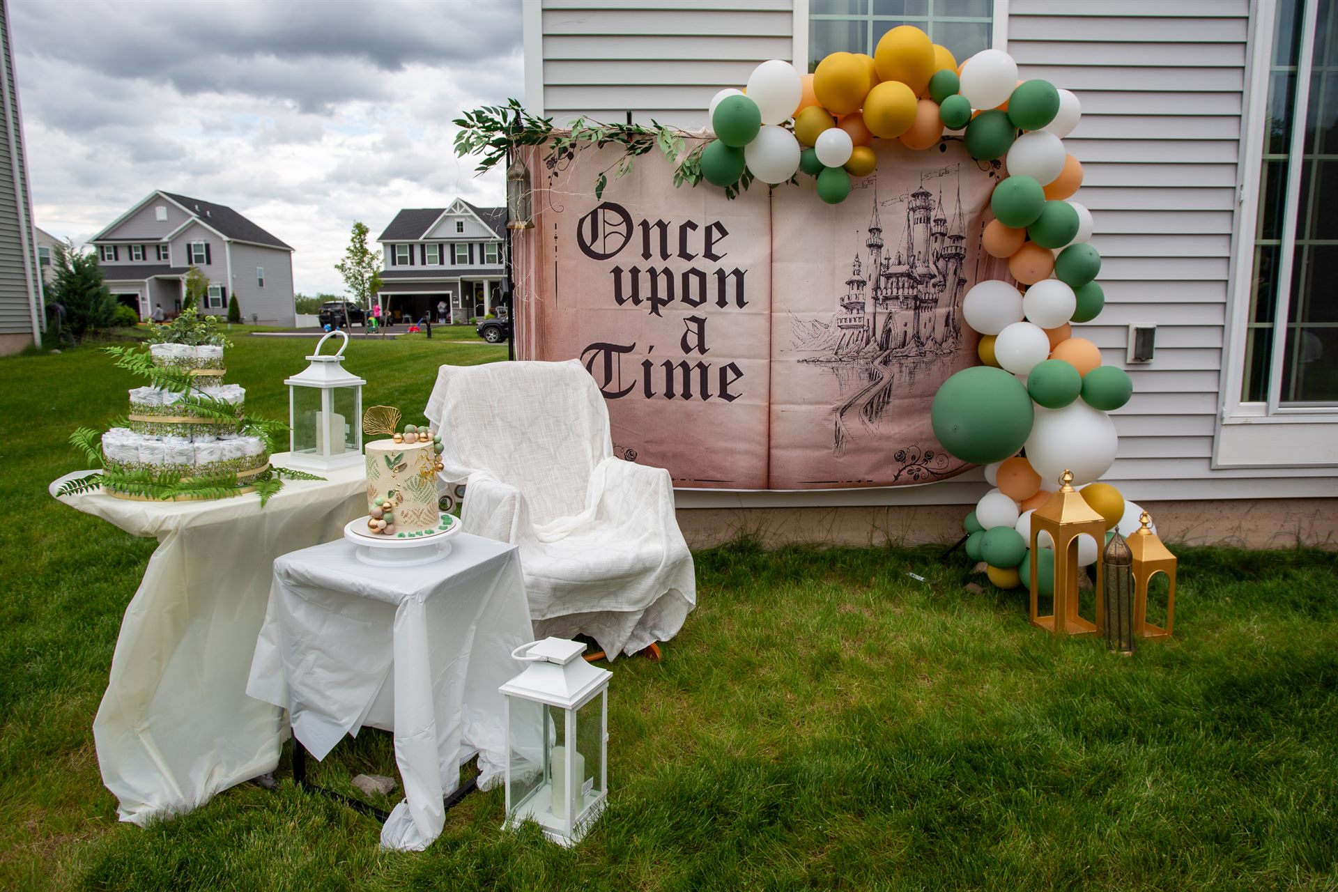 Full fairytale baby shower setup with storybook backdrop, balloon arch, lanterns and dessert tables
